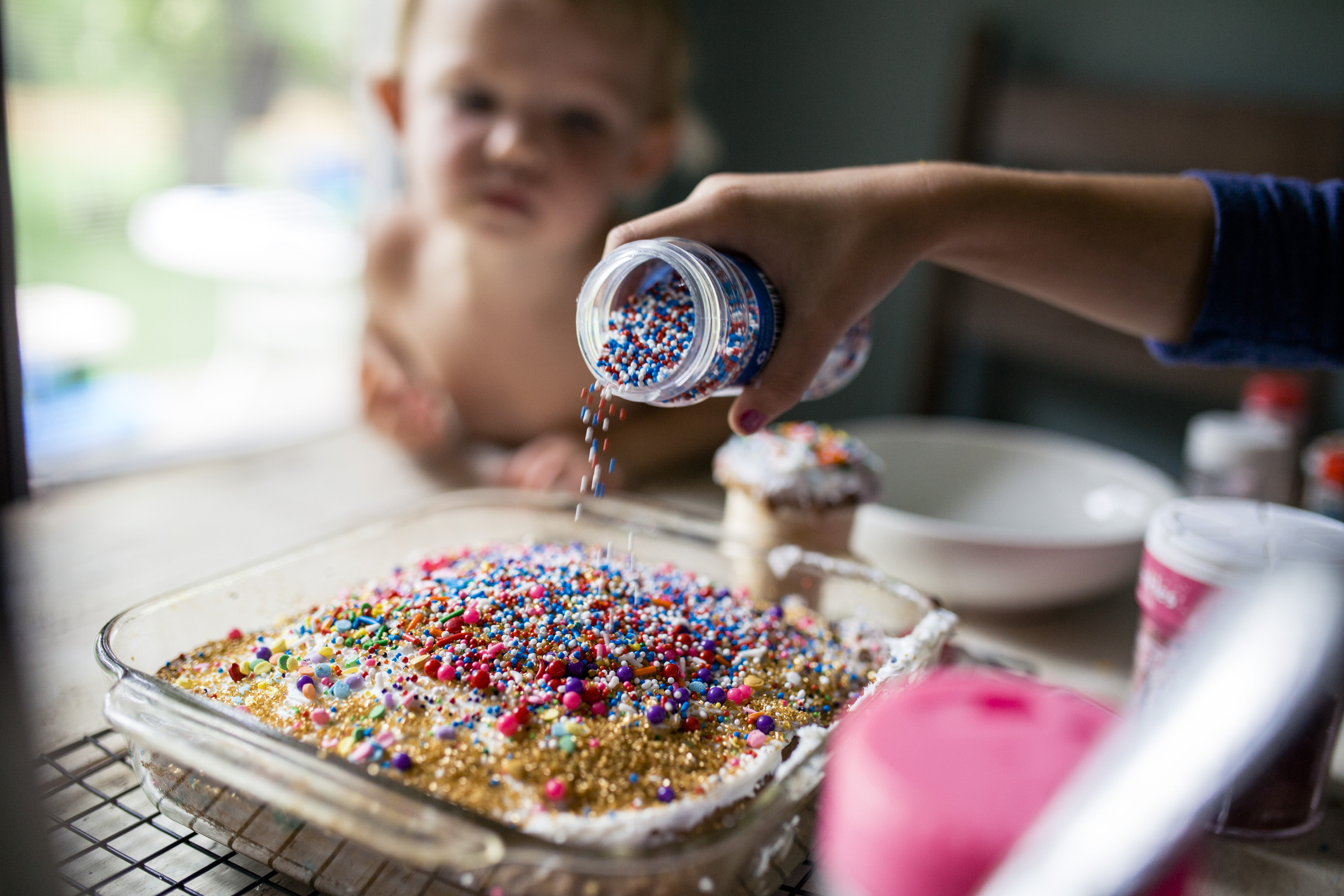 Girl decorating cake with overabundance of sprinkles