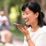 A woman using the speakerphone on her smartphone during a call in a Taipei park.